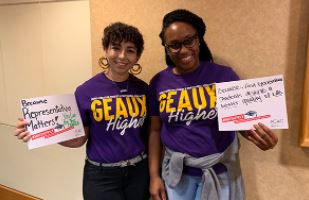 two female, black students holding why apply signs