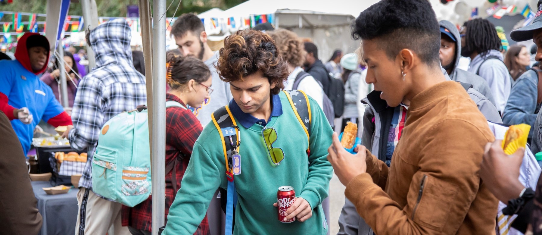 two students eat snacks at an outdoor fair