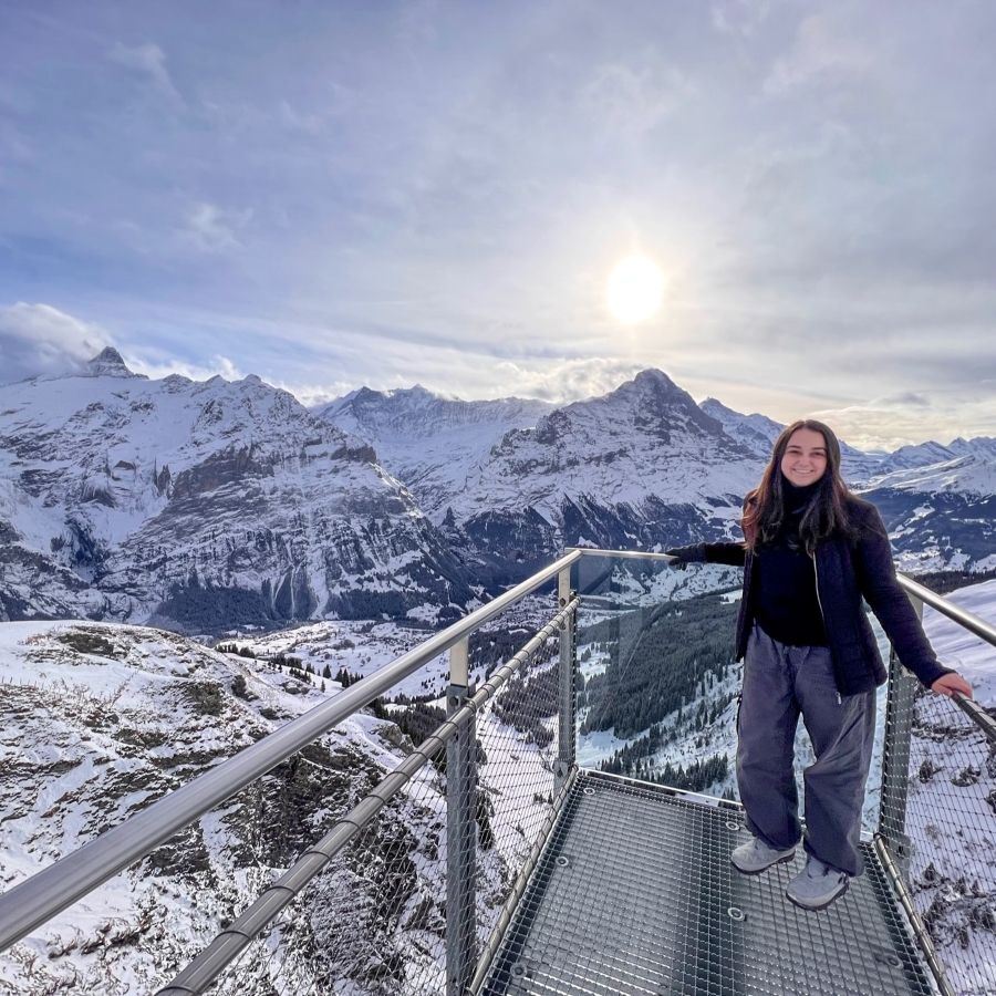 student smiles in front of a majestic mountain range