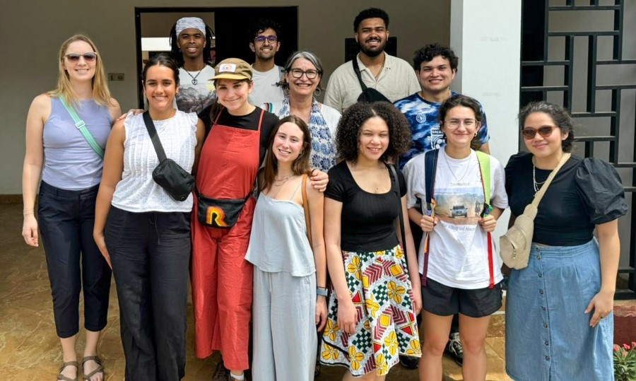 group of ten students and two faculty smile together