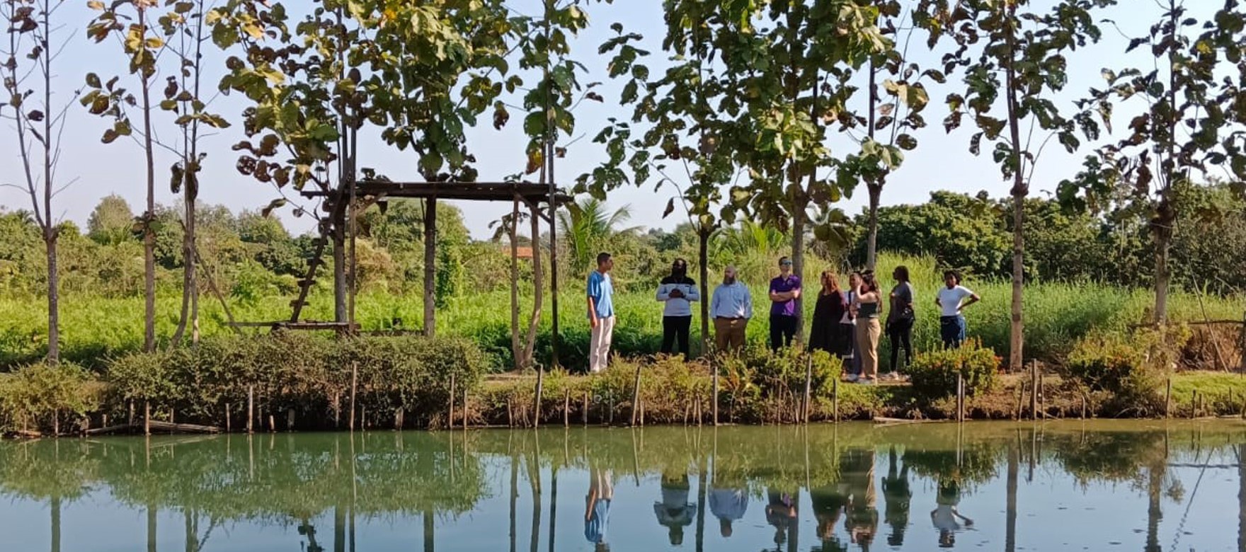 people stand at a distance across a reflective lake