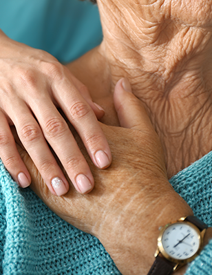 Photo of an older female holding hands with a younger caretaker